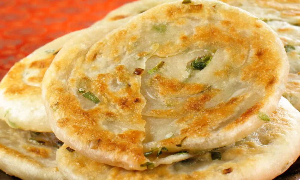 Flaky scallion pancakes stacked with golden-brown crusts at Lucky Dumplings, a Dumpling Restaurant in Great Neck